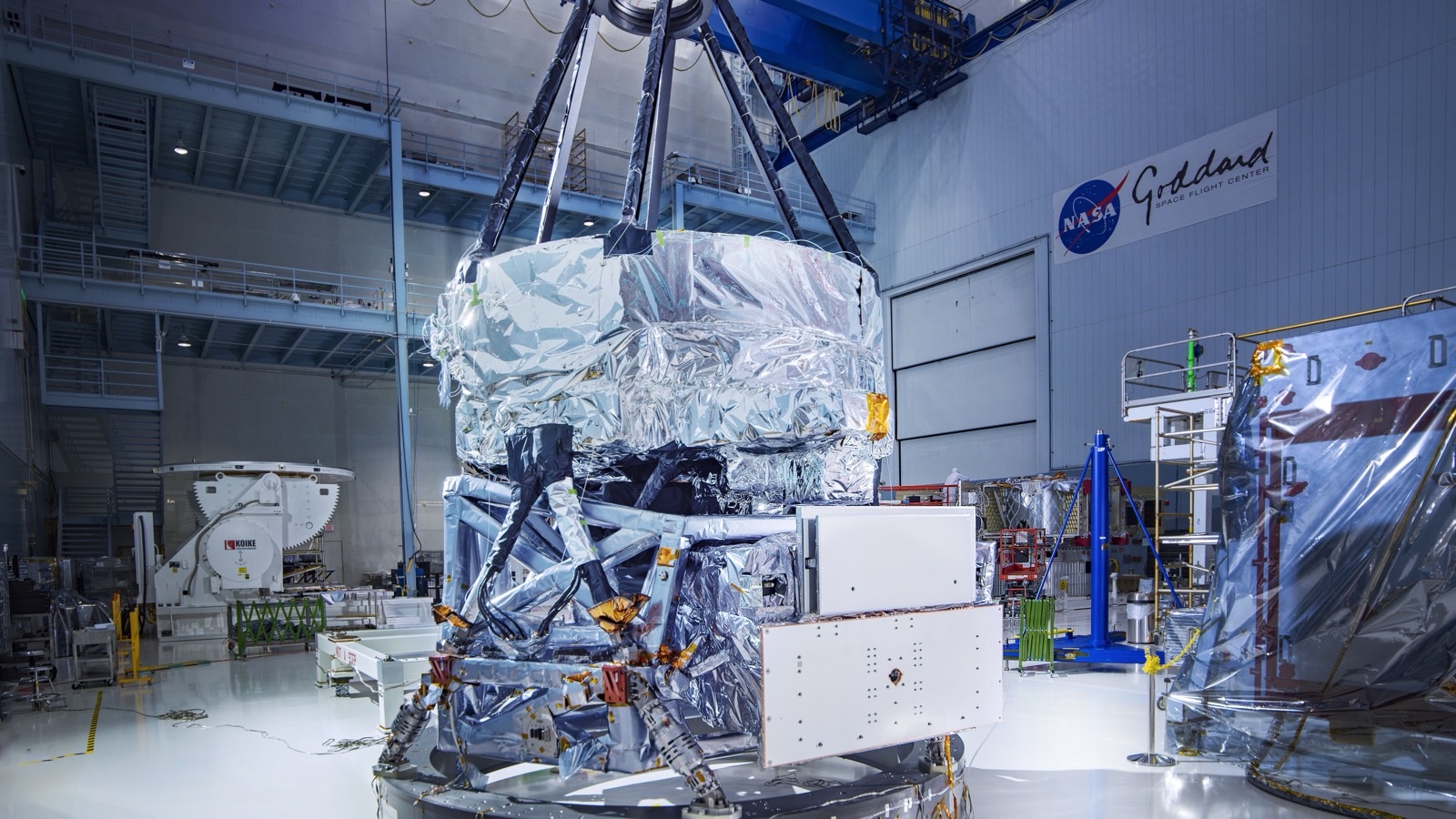The Nancy Grace Roman Space Telescope during assembly, a large gold and silver spacecraft with its wide-field instrument, in a NASA clean room